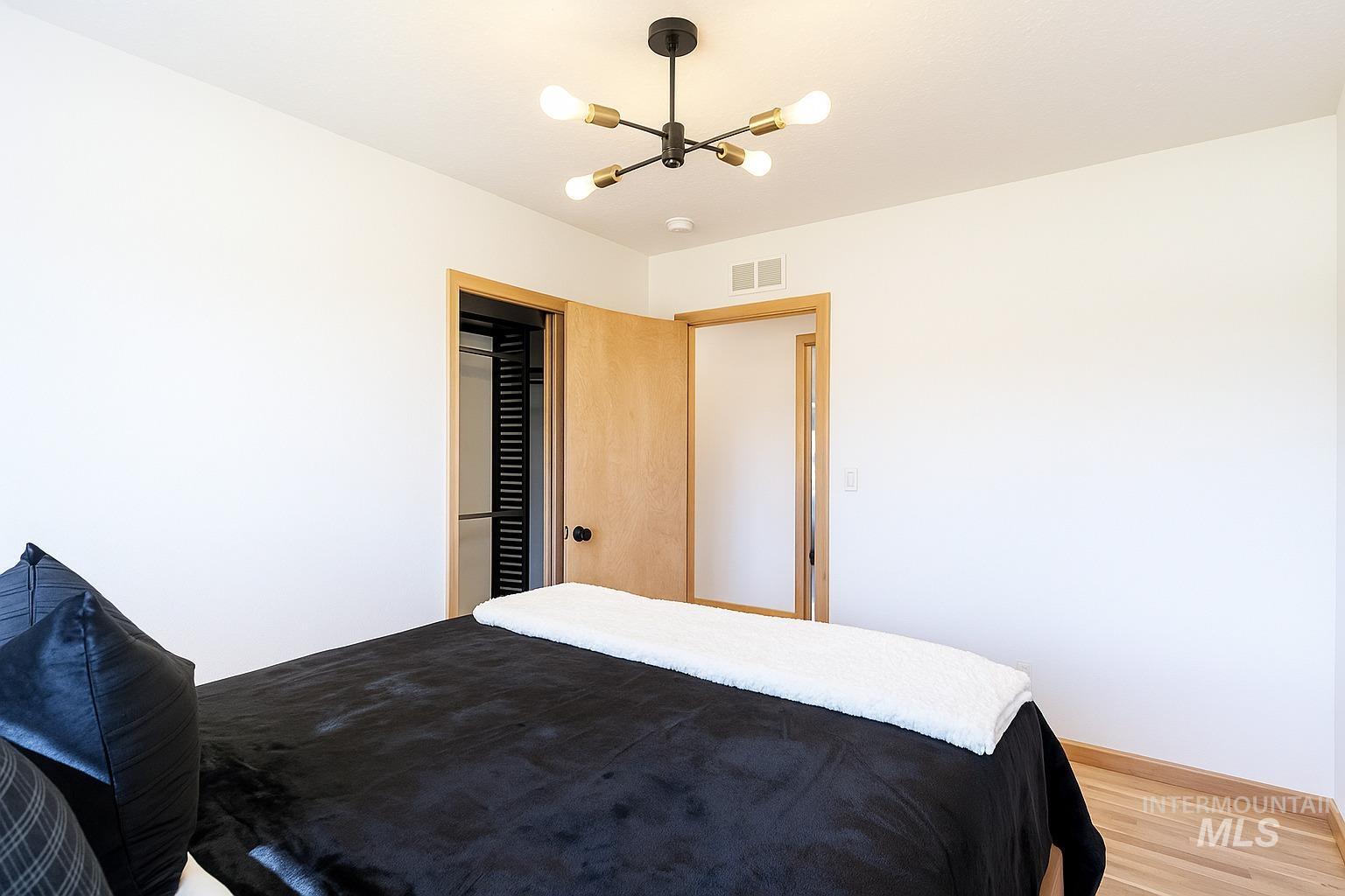 Bedroom featuring wood finished floors and a chandelier