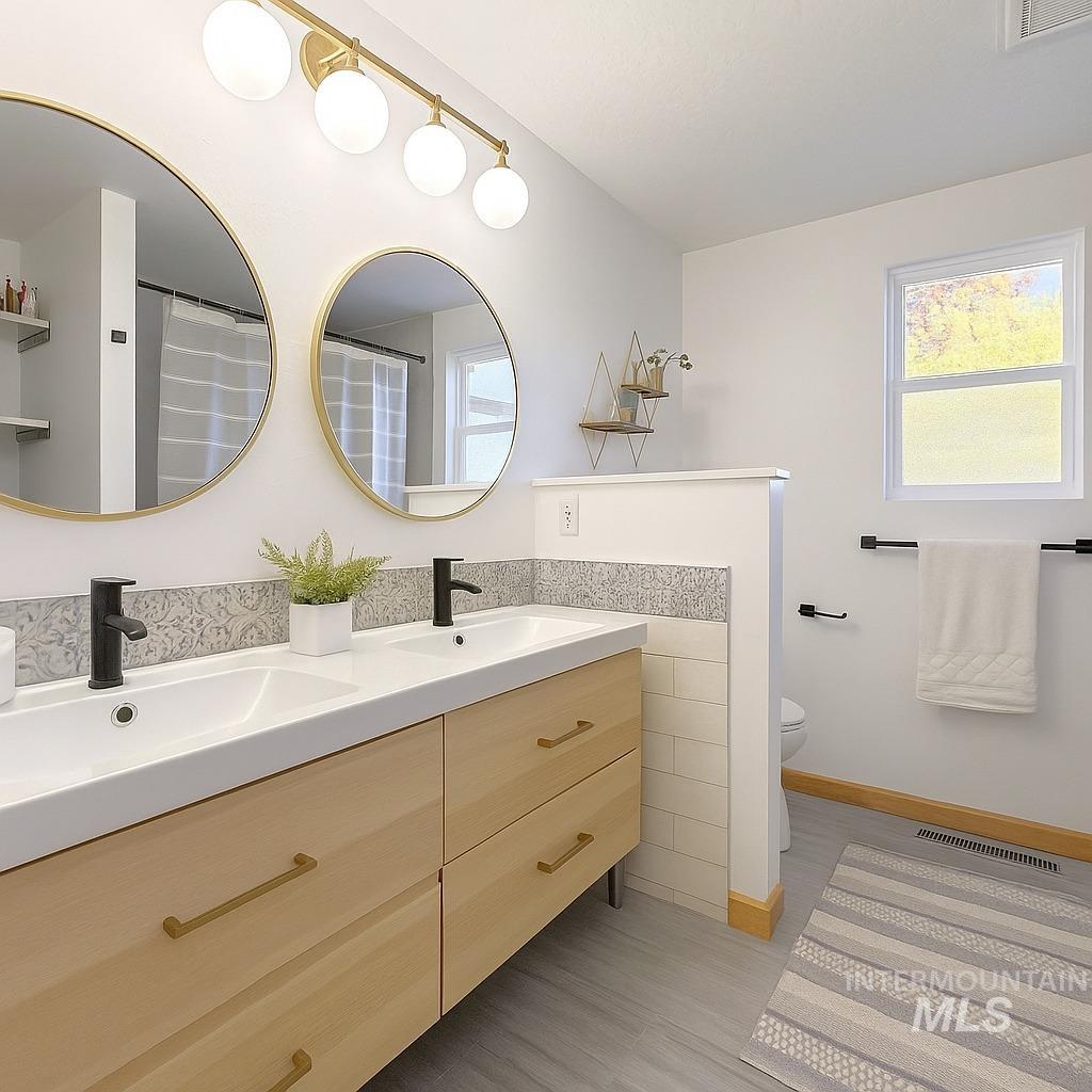Full bath with double vanity, light wood-style floors, and a shower with shower curtain
