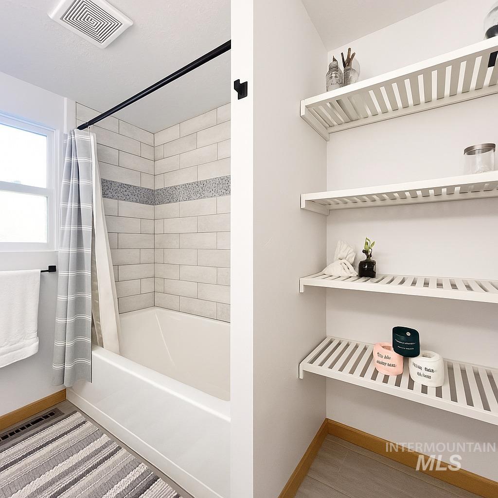Full bath featuring shower / tub combo and baseboards
