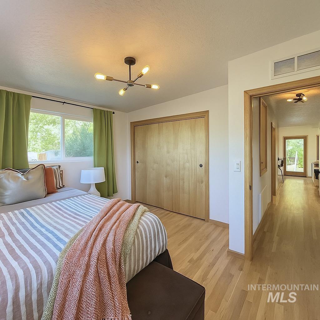 Bedroom featuring a textured ceiling, a closet, wood finished floors, and a chandelier