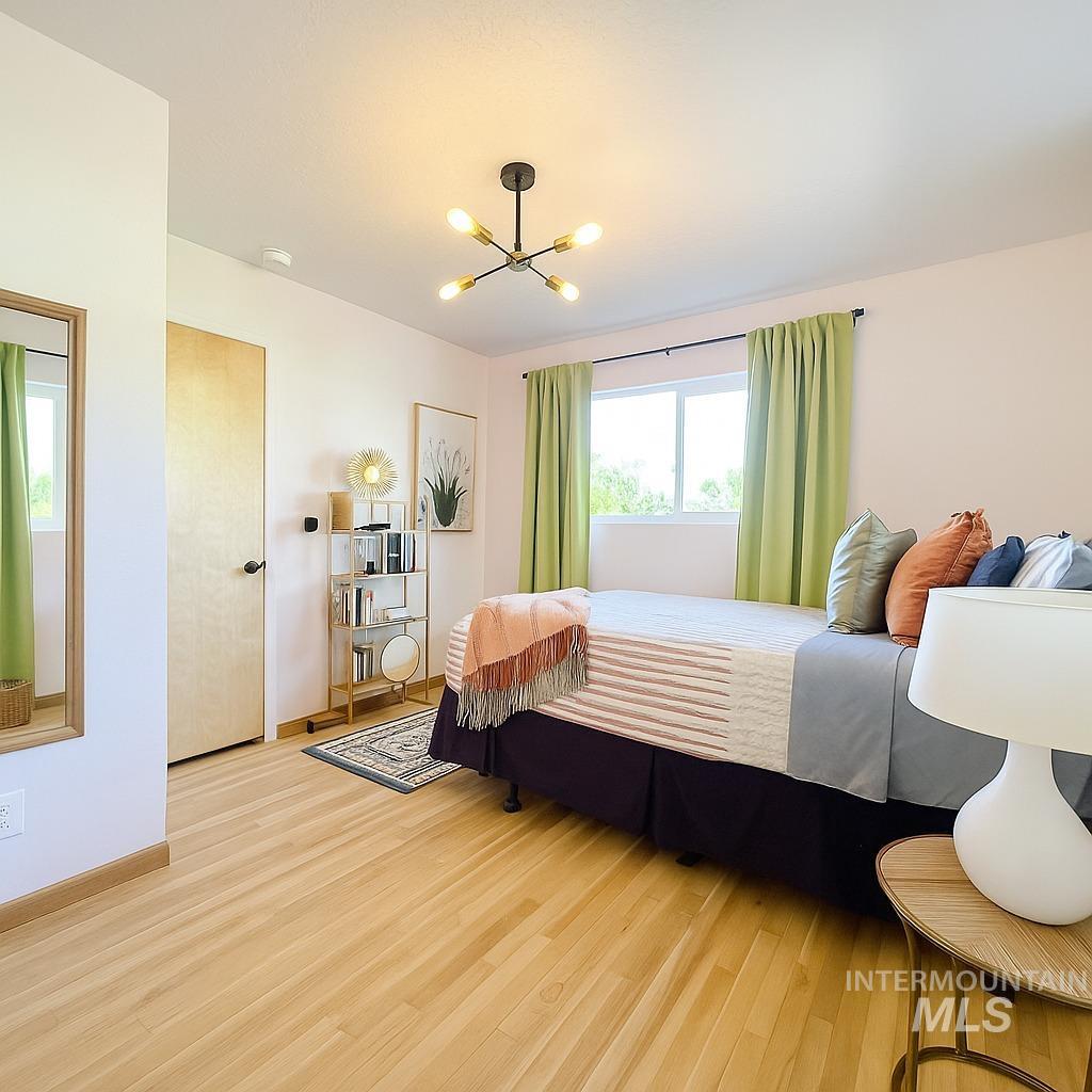 Bedroom featuring light wood finished floors and a chandelier