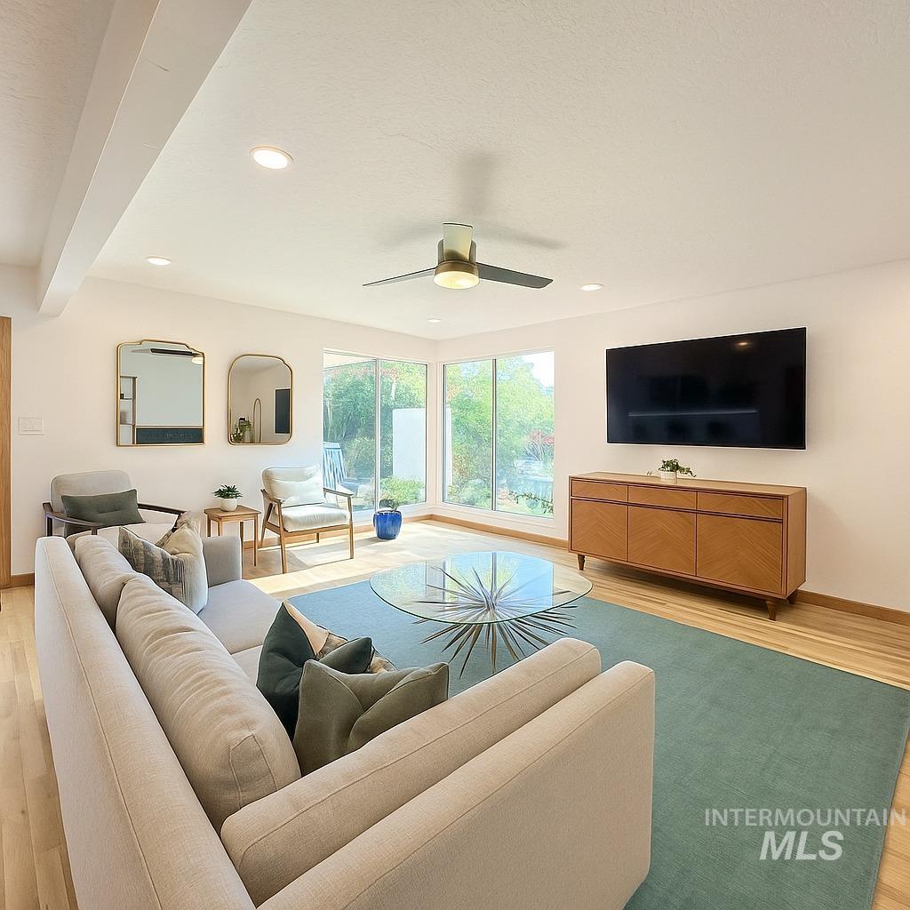 Living area with light wood finished floors, beamed ceiling, recessed lighting, and a ceiling fan