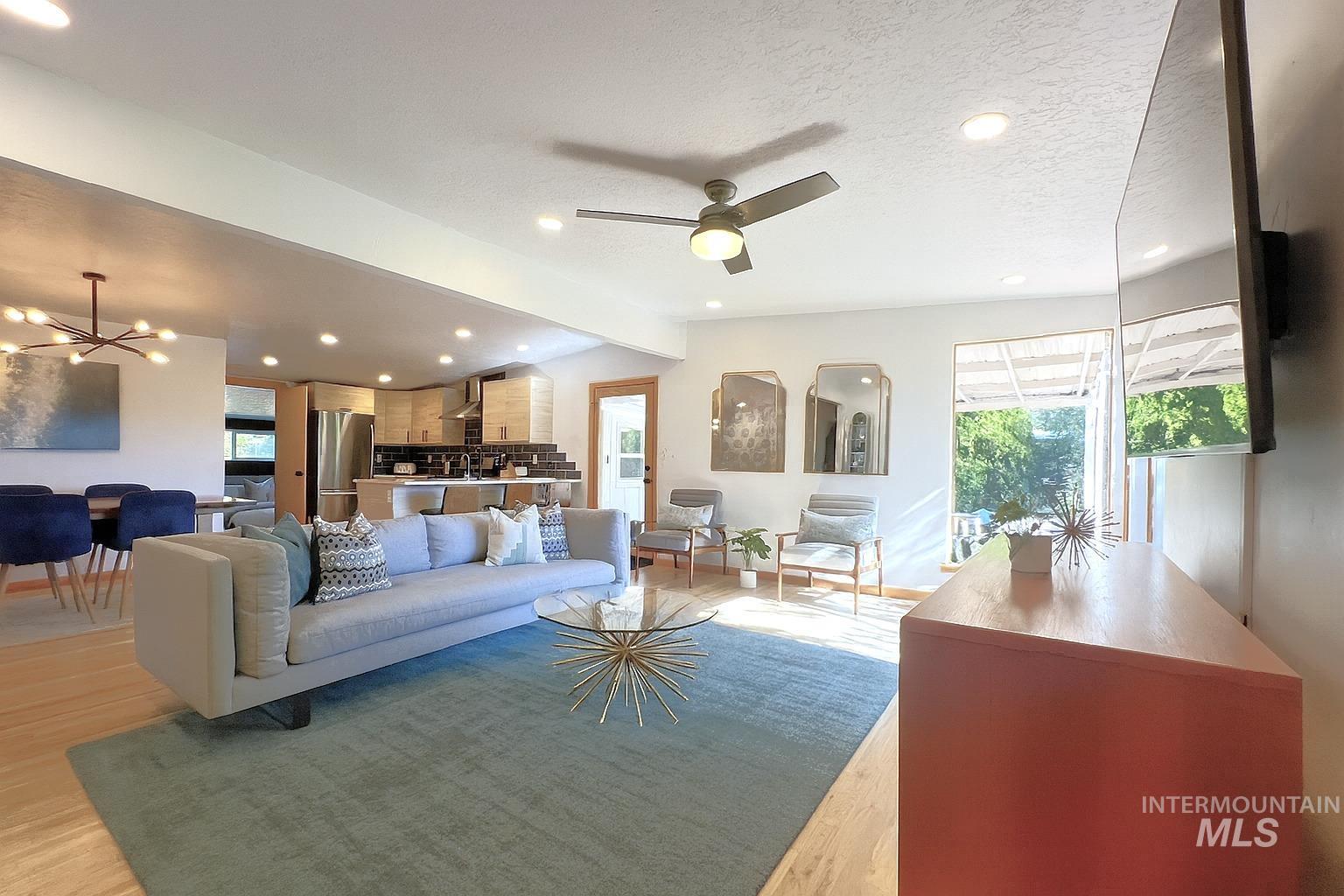 Living room with a chandelier, light wood-style flooring, recessed lighting, ceiling fan, and a textured ceiling