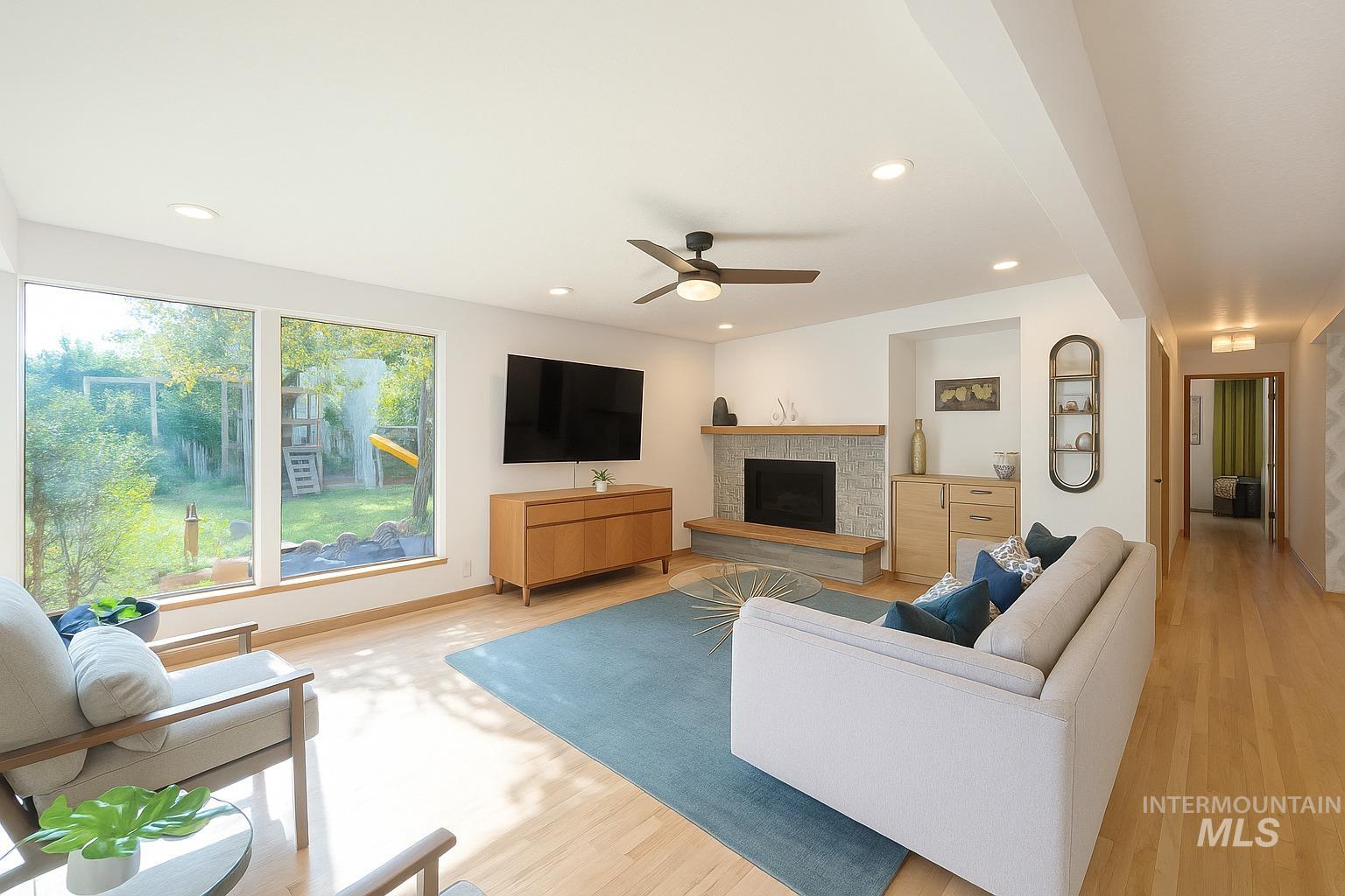 Living room featuring wood finished floors, a fireplace with raised hearth, recessed lighting, and a ceiling fan
