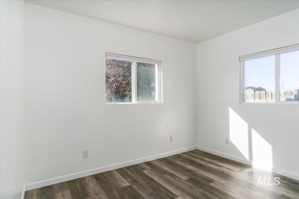 Unfurnished room with dark wood-style floors and baseboards