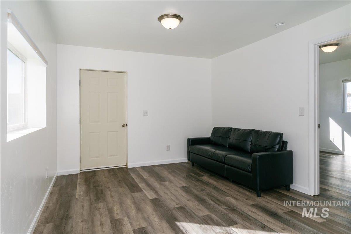 Living area featuring dark wood-type flooring and baseboards