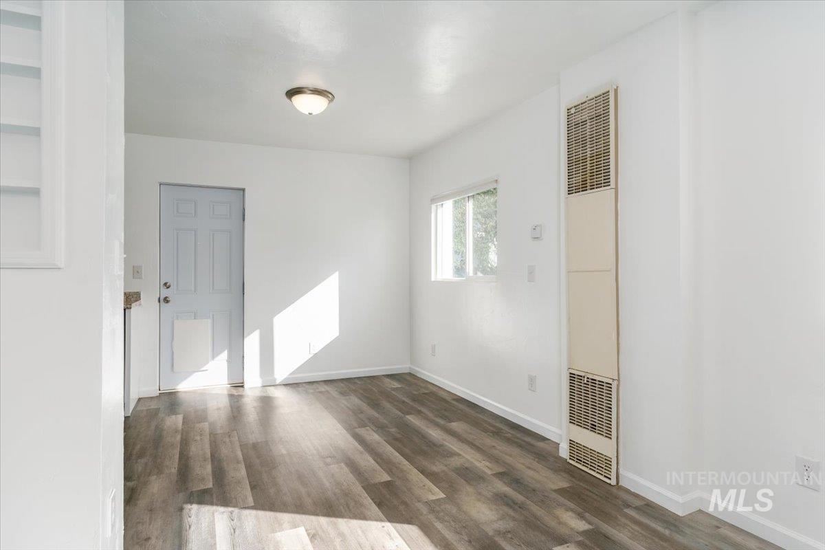 Spare room with dark wood-type flooring and a heating unit