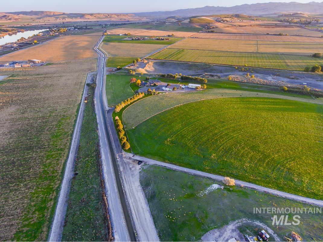 Aerial overview of property's location featuring large plots for crops, rural landscape, and a mountain backdrop