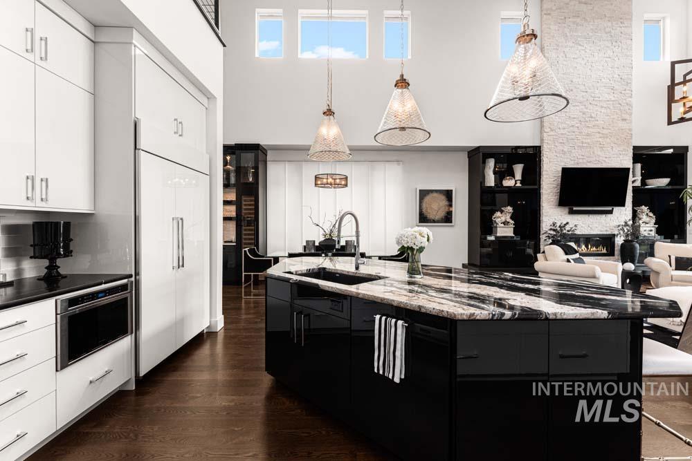 Kitchen featuring a fireplace, a high ceiling, dark cabinets, dark wood-type flooring, and white cabinets