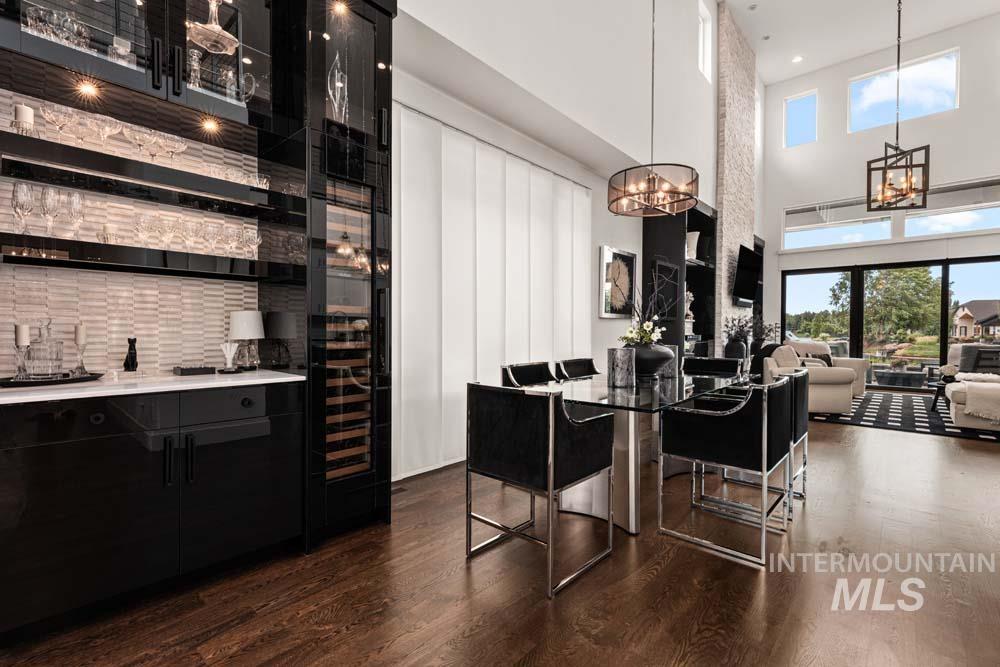 Bar with a chandelier, dark wood-style floors, plenty of natural light, a high ceiling, and hanging light fixtures