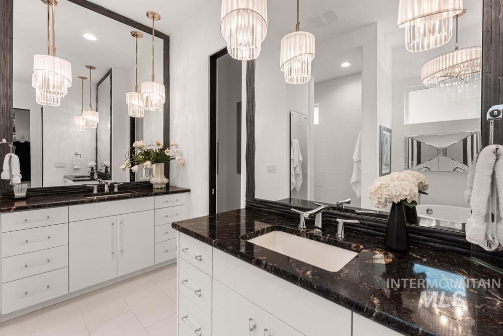 Bathroom with a chandelier, two vanities, tile patterned flooring, and recessed lighting