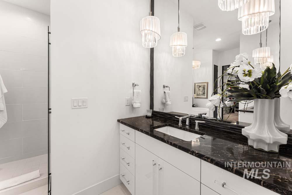 Bathroom with a chandelier, vanity, and tiled shower