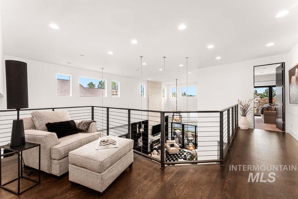 Sitting room featuring wood finished floors, plenty of natural light, recessed lighting, and an upstairs landing