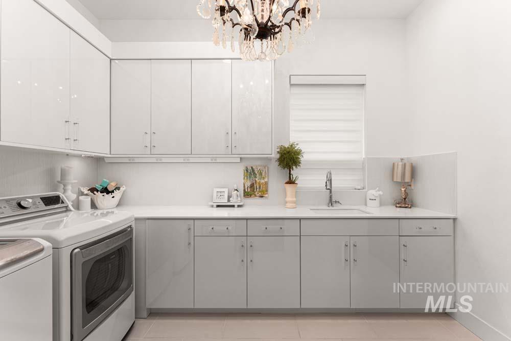 Laundry area with independent washer and dryer, cabinet space, a chandelier, and light tile patterned floors