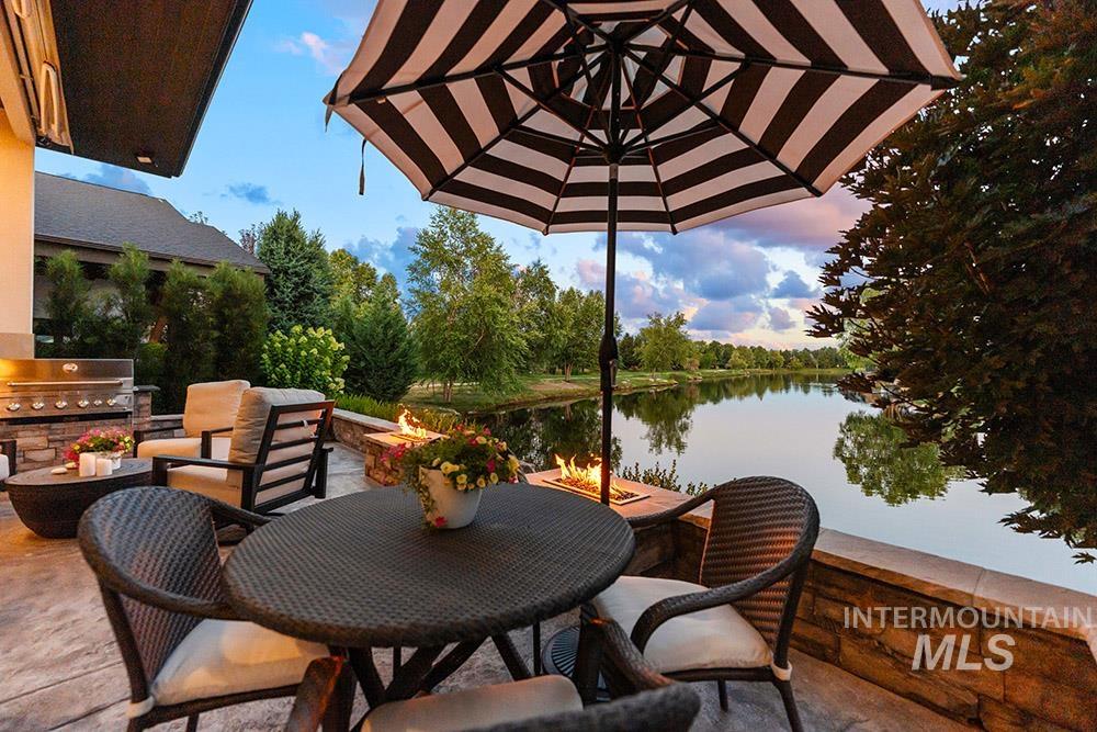 View of patio / terrace with a fire pit, exterior kitchen, a water view, and outdoor dining space