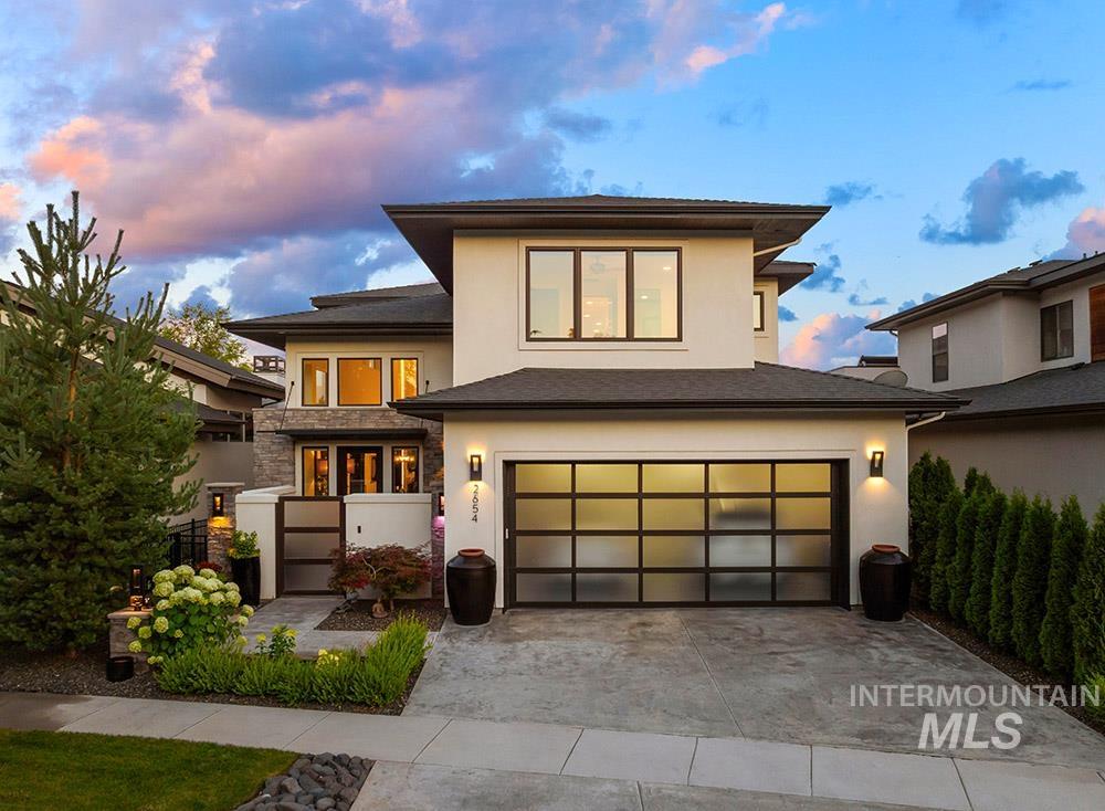 Prairie-style home featuring stucco siding, a garage, concrete driveway, and stone siding