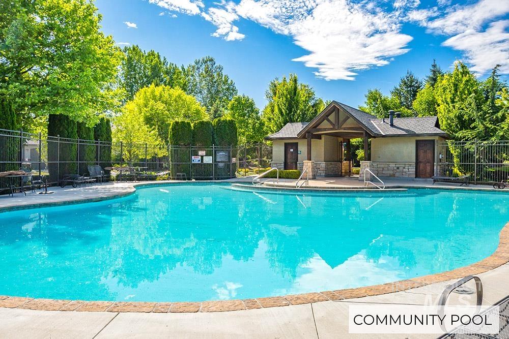 Community pool with a patio and view of wooded area