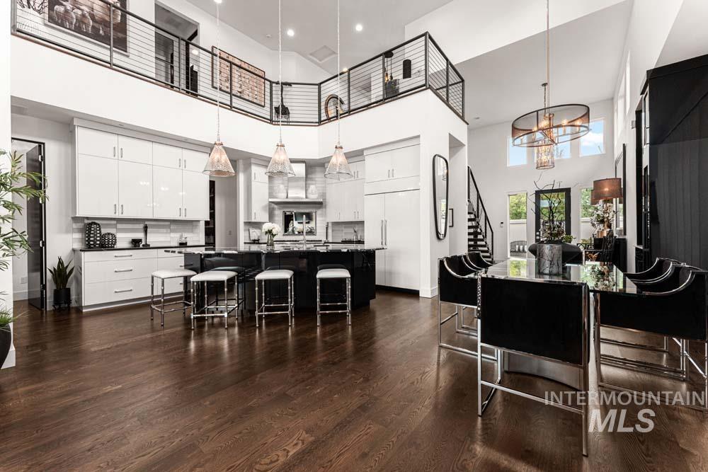 Kitchen with a high ceiling, dark countertops, a kitchen bar, dark wood-style floors, and pendant lighting