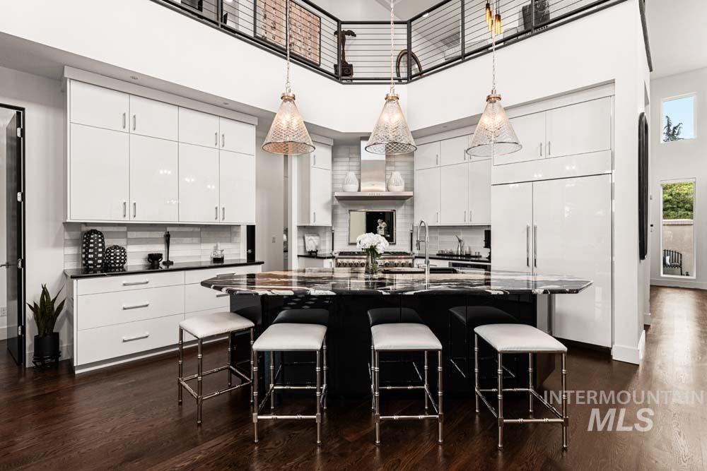 Kitchen with a high ceiling, dark countertops, paneled built in refrigerator, dark wood-style floors, and tasteful backsplash