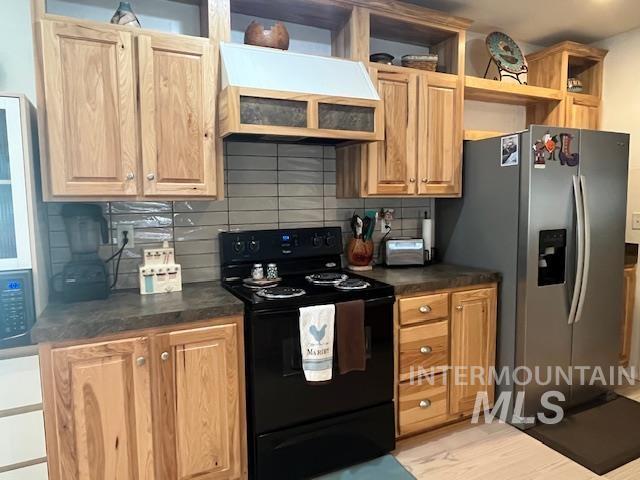 Kitchen with stainless steel appliances, backsplash, custom range hood, and dark countertops