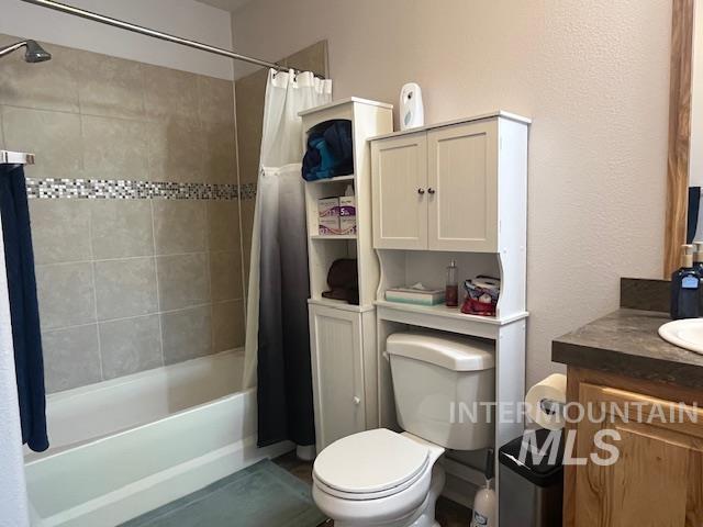 Full bath with vanity, shower / bath combination with curtain, and a textured wall