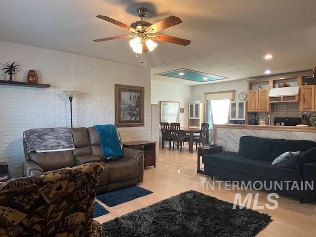 Living room with light wood-style flooring, ceiling fan, and recessed lighting