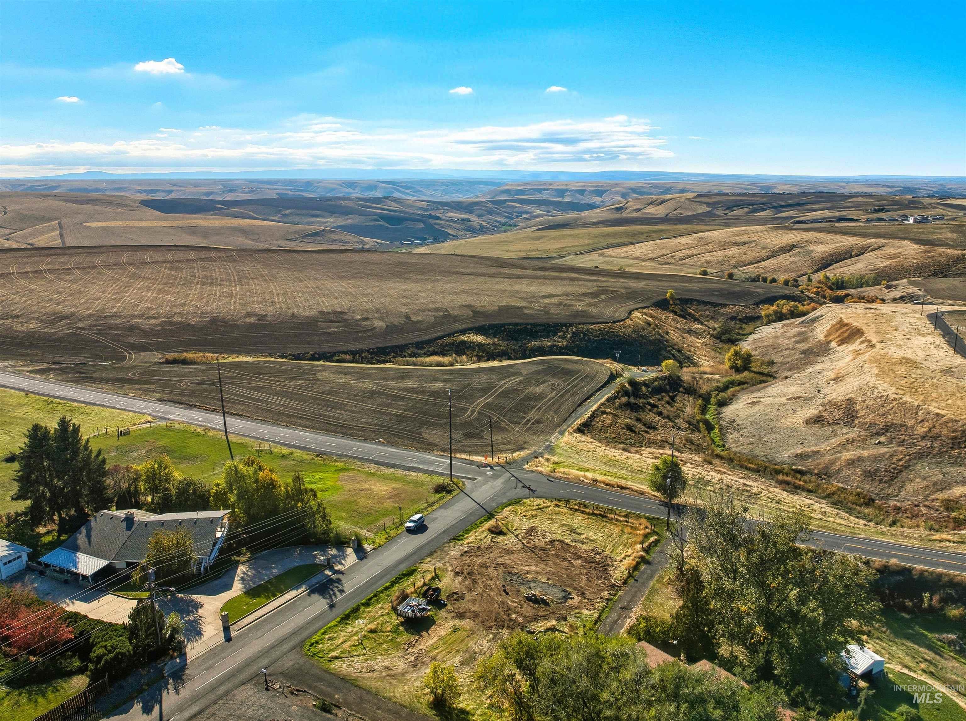 Aerial view of property and surrounding area featuring rural landscape and a mountainous background