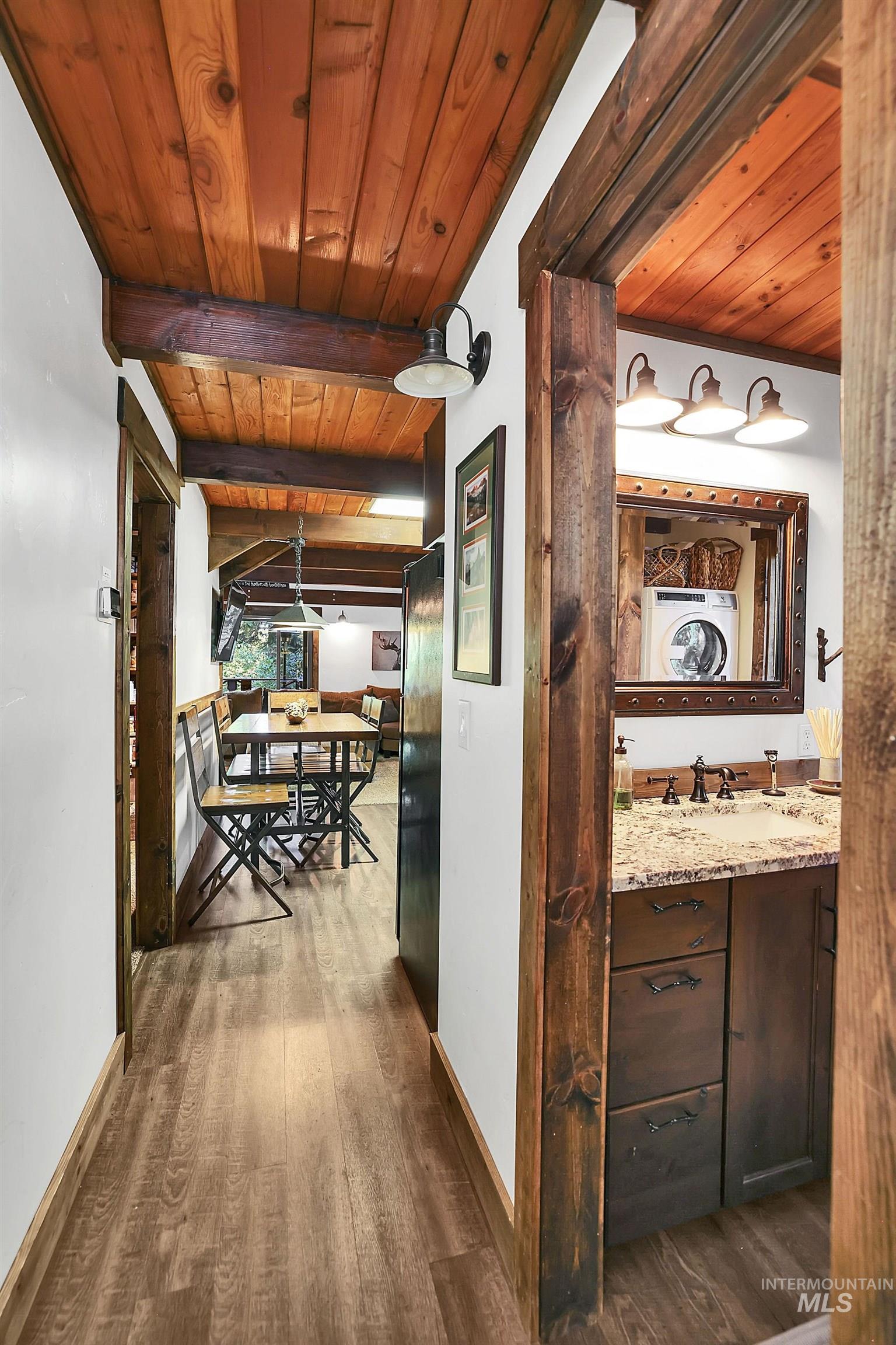 Hall with a wooden ceiling with exposed beams, dark wood-style floors, and washer / clothes dryer