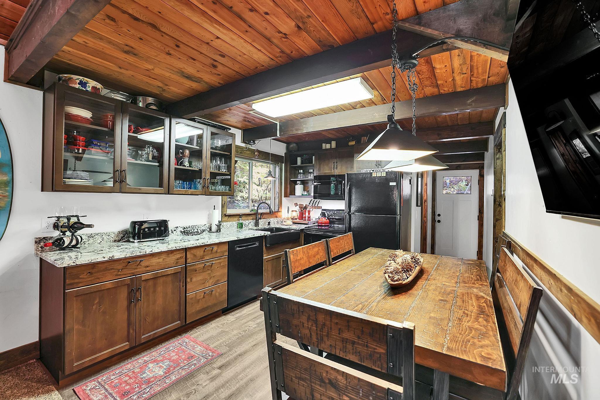 Kitchen with black appliances, pendant lighting, glass insert cabinets, open shelves, and a wood ceiling with exposed beams