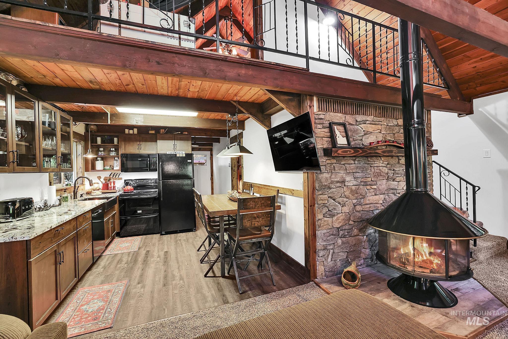 Bar with a wood ceiling with exposed beams, open shelves, light wood-type flooring, a wood stove, and black appliances