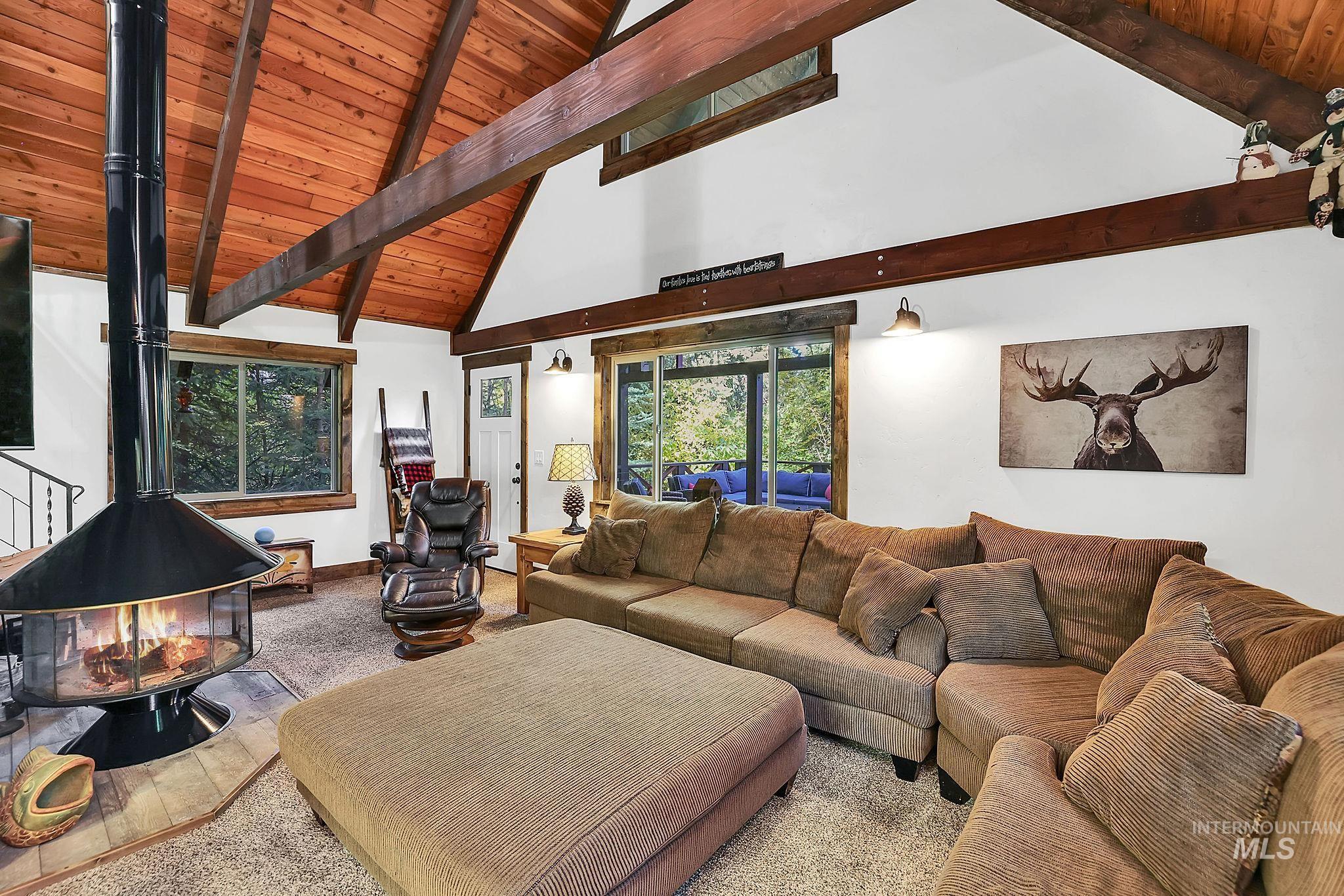 Living room featuring high vaulted ceiling, a wood ceiling with exposed beams, and a wood stove