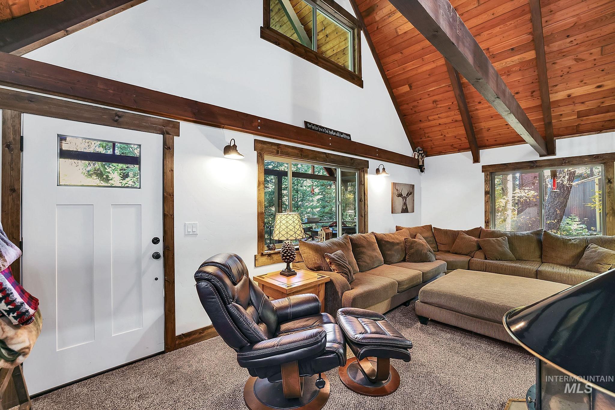 Living area with a wood ceiling with exposed beams, carpet flooring, and high vaulted ceiling