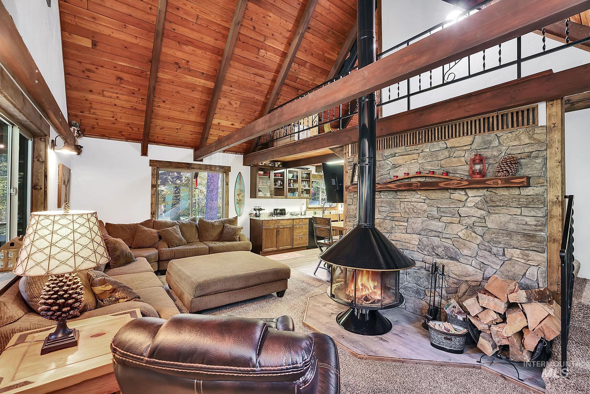 Living area with a wooden ceiling with exposed beams, high vaulted ceiling, and a wood stove