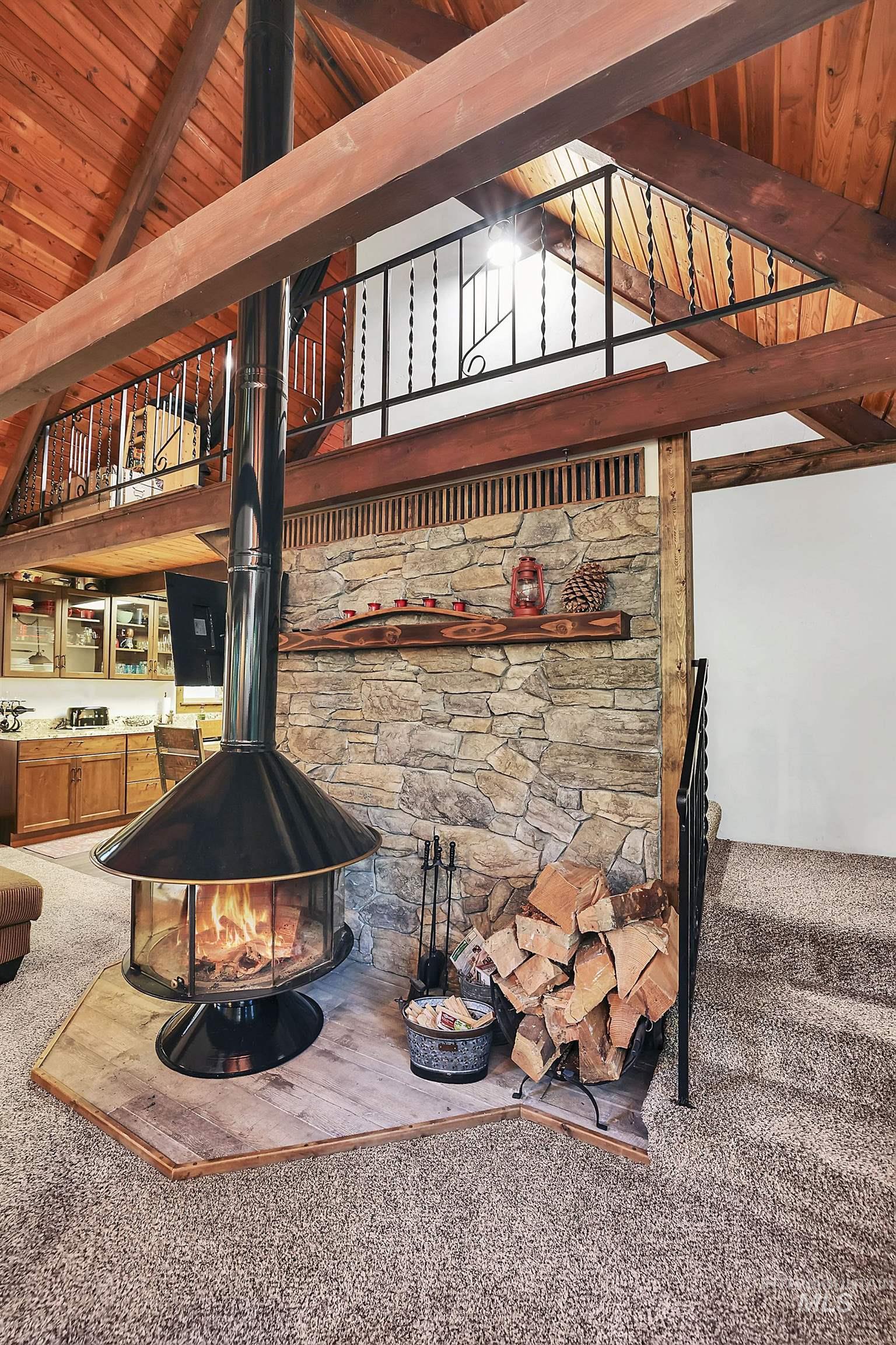 Detailed view of carpet, a wood stove, a wood ceiling with exposed beams, and a fire pit