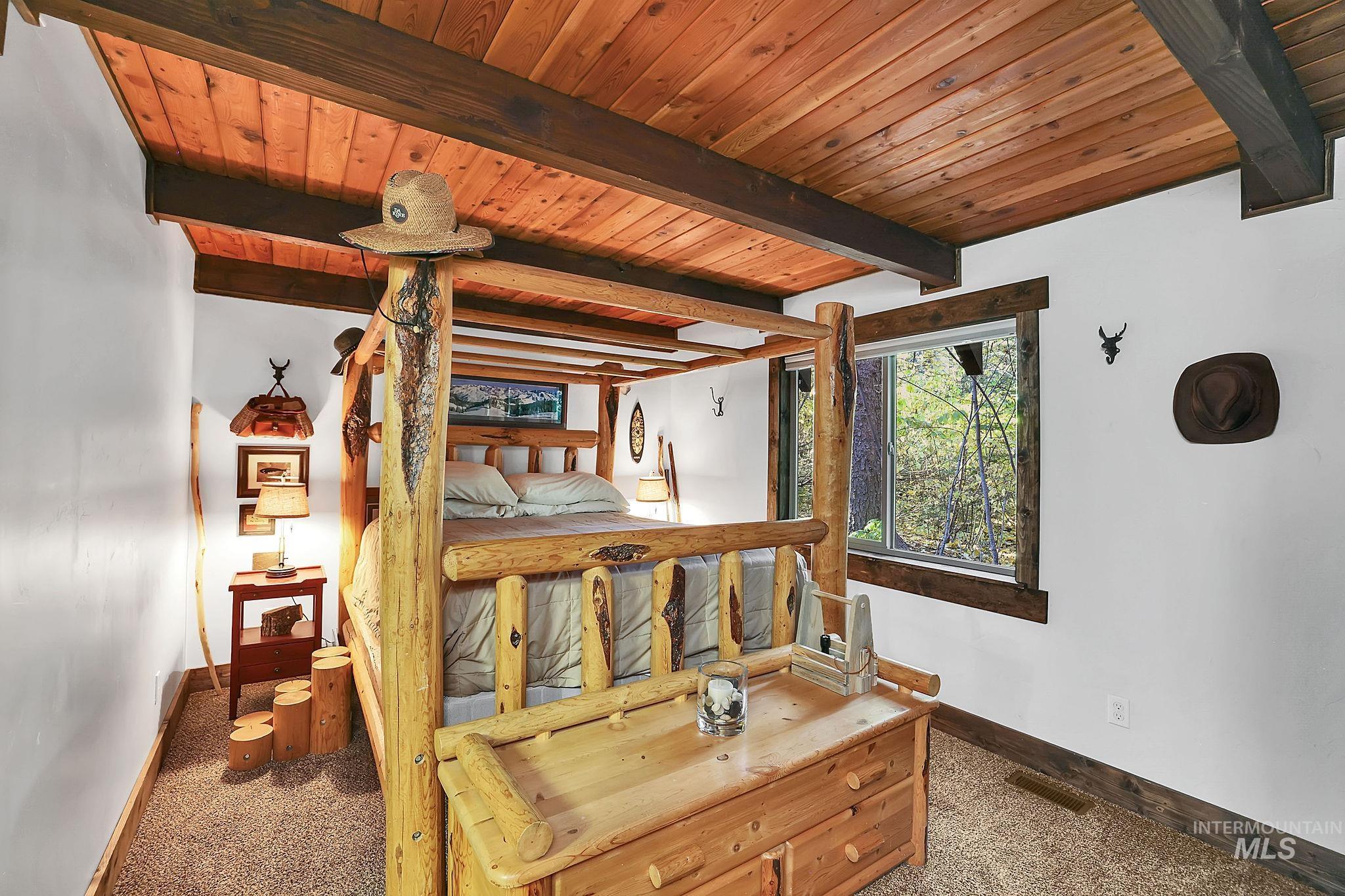 Bedroom with dark carpet and a wood ceiling with exposed beams