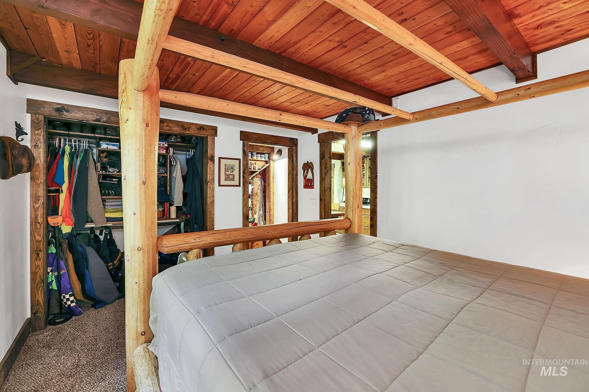 Carpeted bedroom featuring a closet and a wooden ceiling with exposed beams