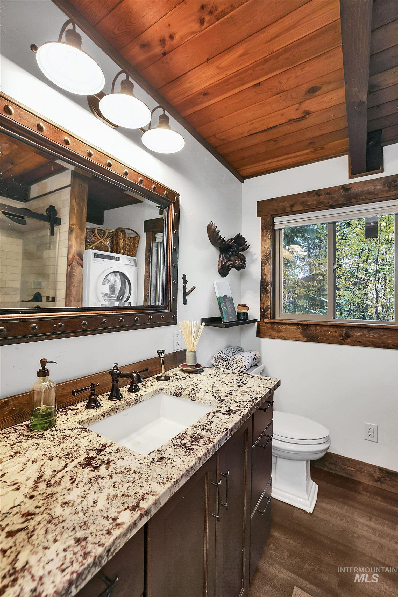 Full bath with wood ceiling, vanity, dark wood-style flooring, a shower stall, and washer / clothes dryer