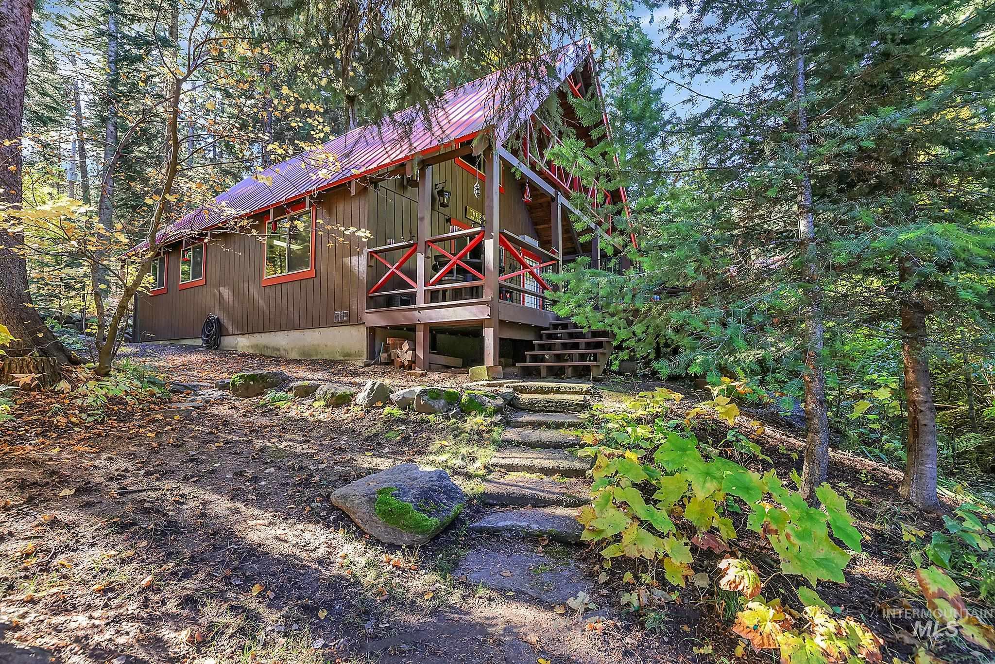 Back of property with a metal roof, a deck, and a view of trees