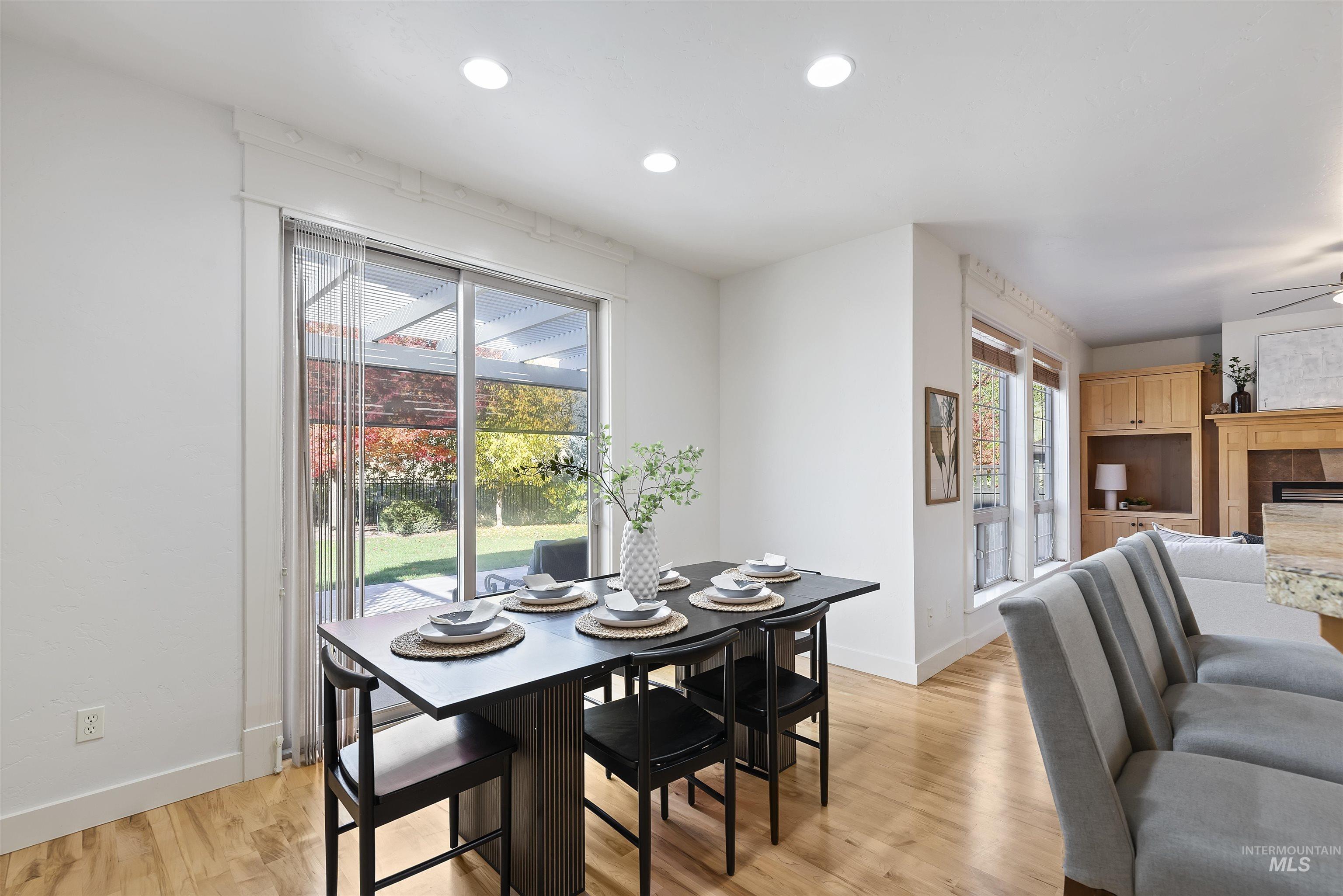 Dining space featuring light wood finished floors, a tiled fireplace, recessed lighting, and a ceiling fan