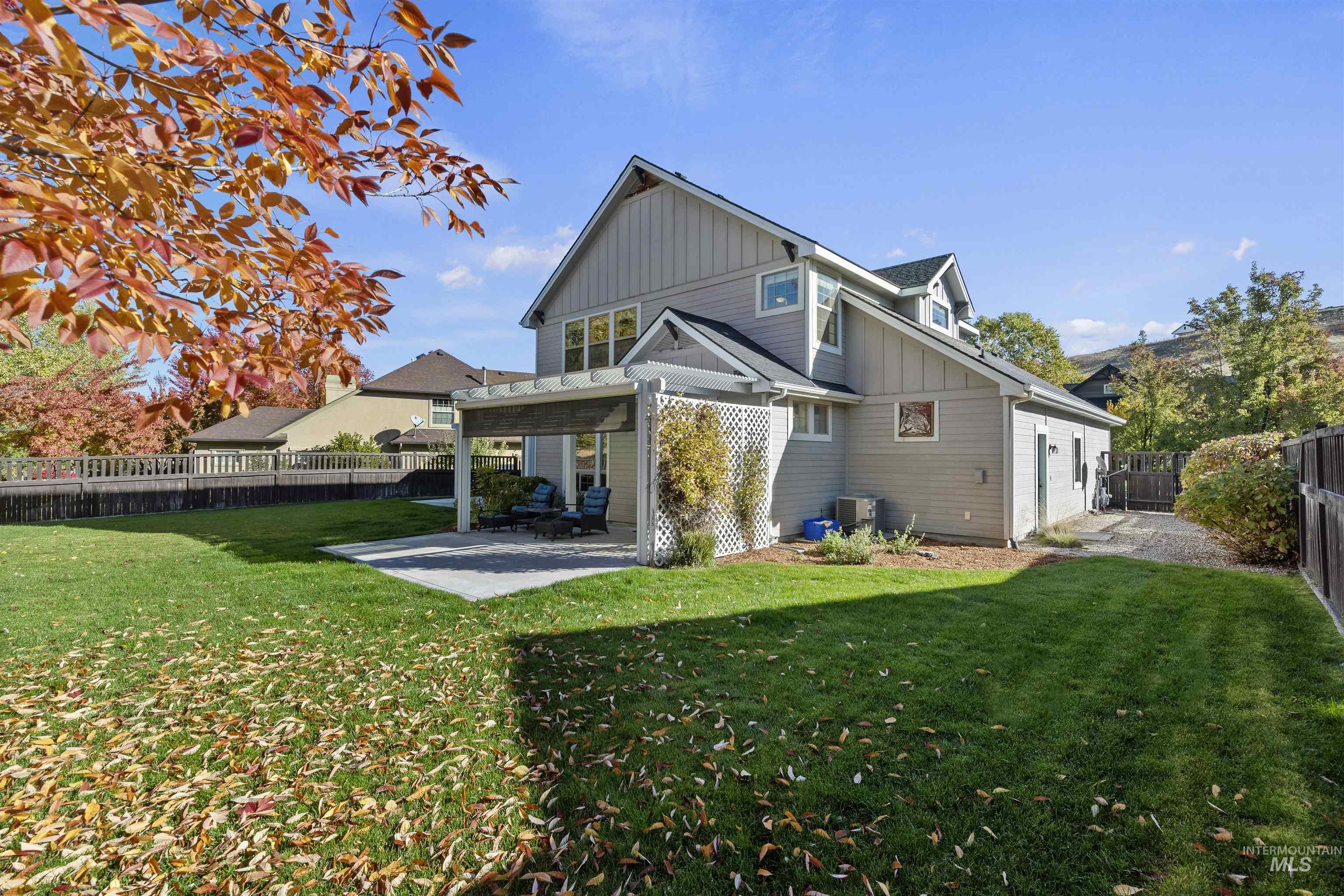 Rear view of house with board and batten siding, a patio, and a fenced backyard