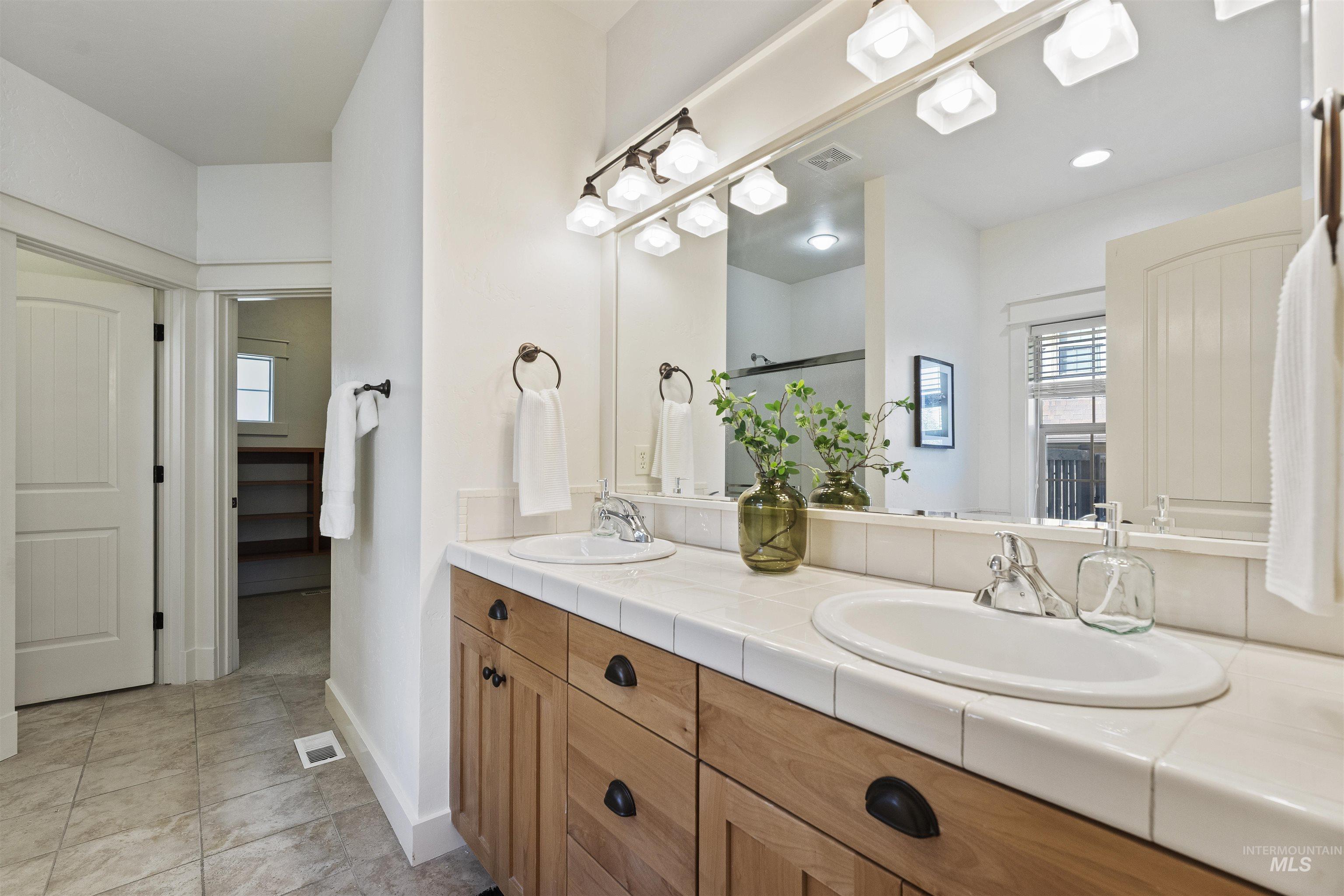 Full bath featuring double vanity and light tile patterned flooring