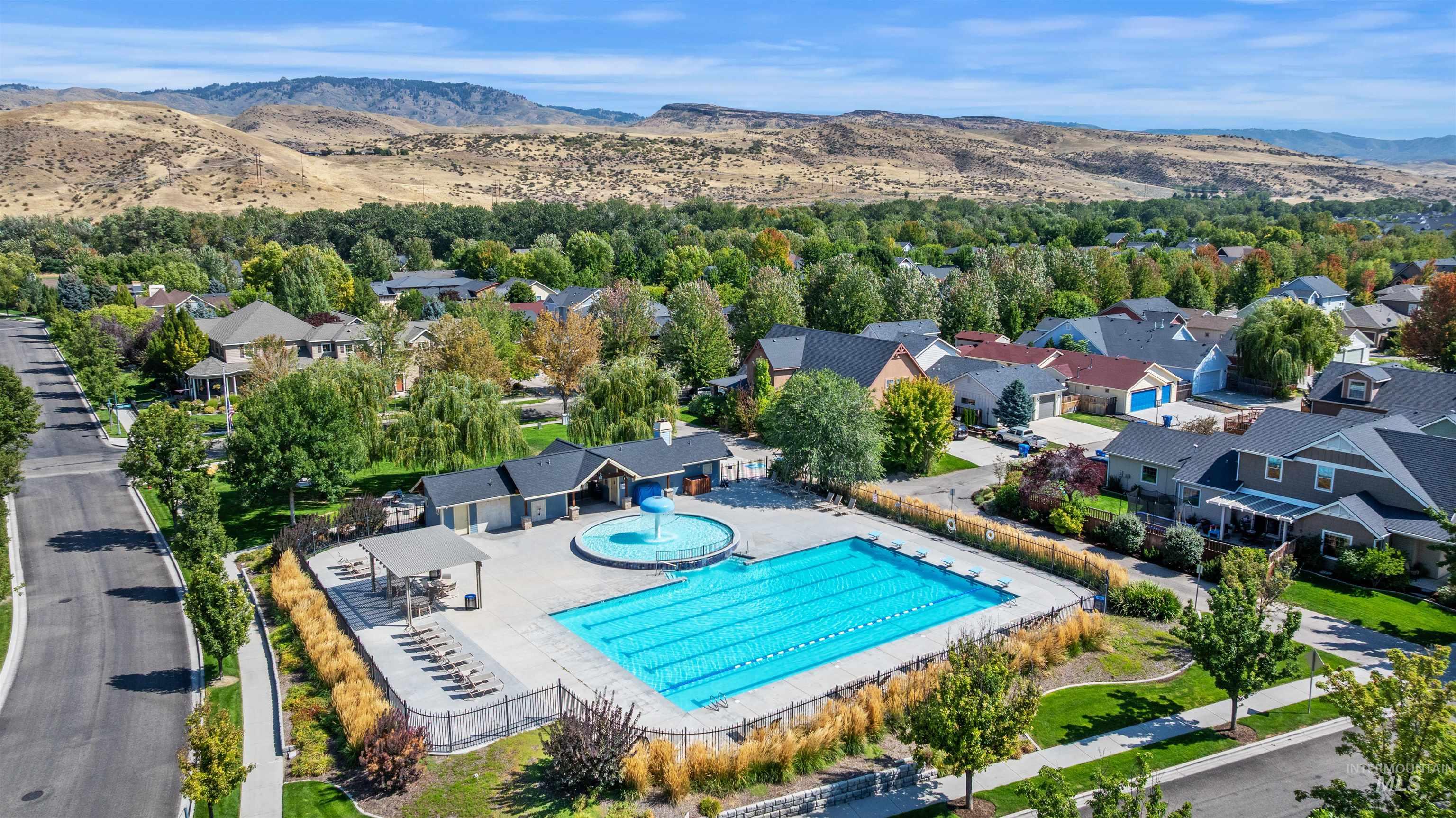 Aerial perspective of suburban area featuring a mountain backdrop and a pool area