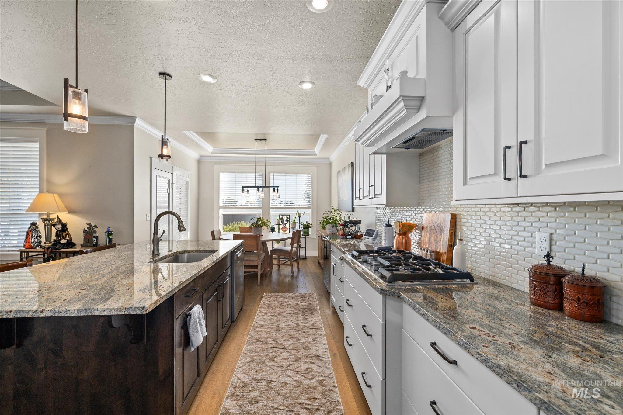 Kitchen with a tray ceiling, white cabinets, backsplash, dark stone counters, and a textured ceiling