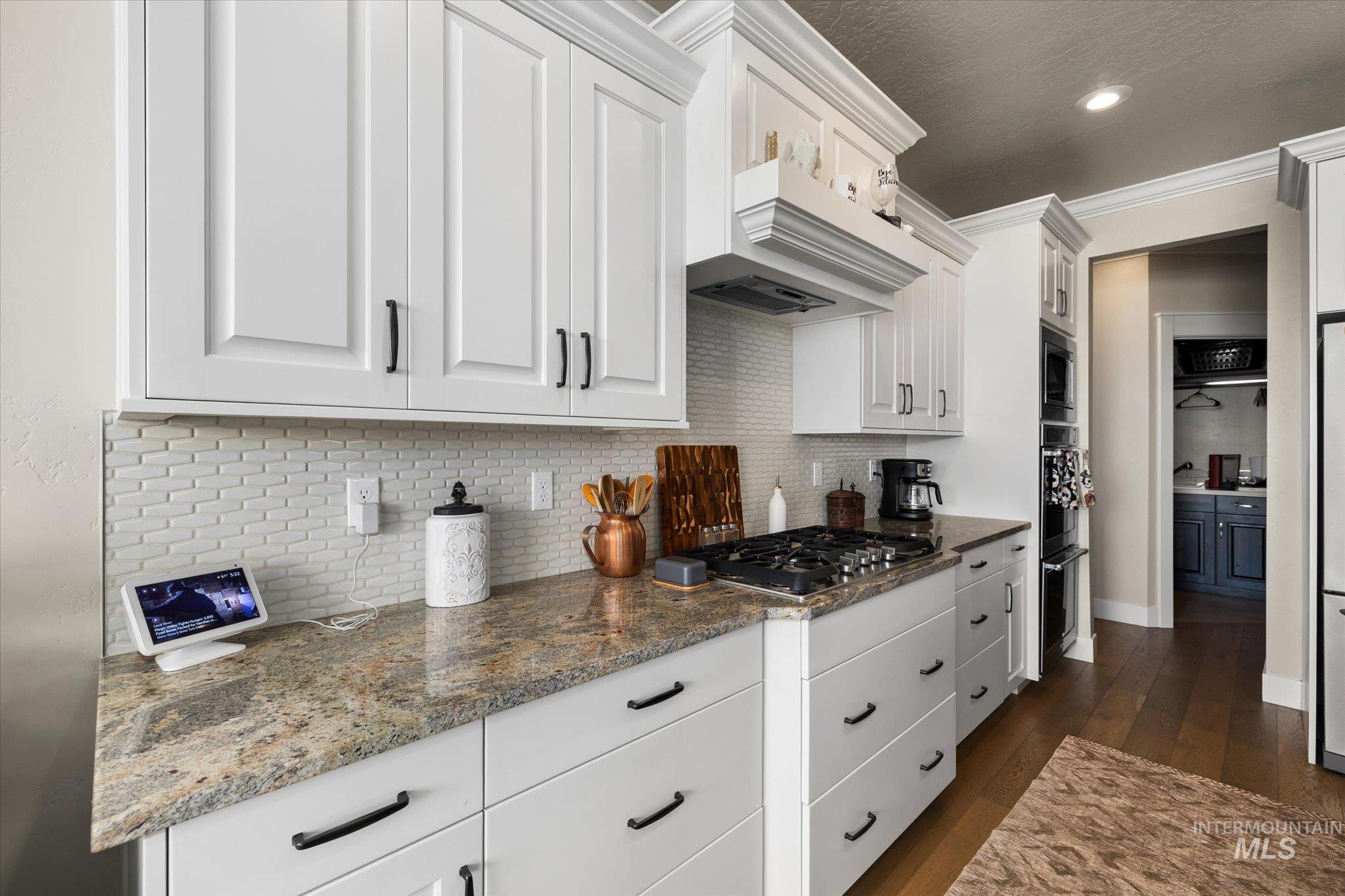 Kitchen featuring decorative backsplash, white cabinets, dark wood-style flooring, crown molding, and recessed lighting