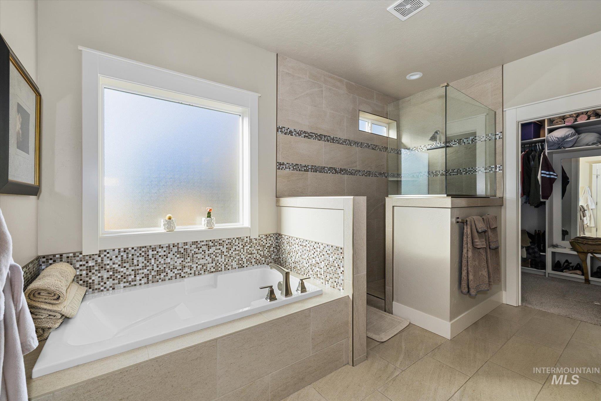 Bathroom featuring walk in shower, a bath, tile patterned floors, and a spacious closet