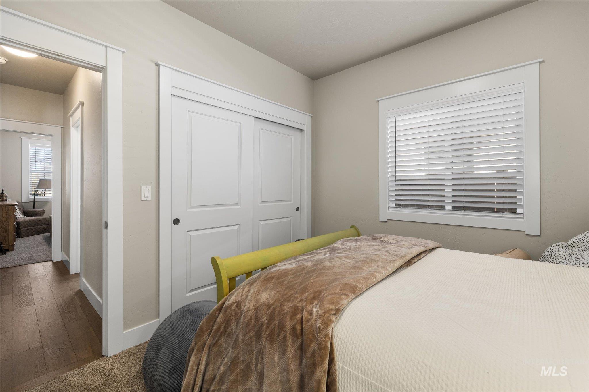 Carpeted bedroom featuring a closet, multiple windows, and wood finished floors