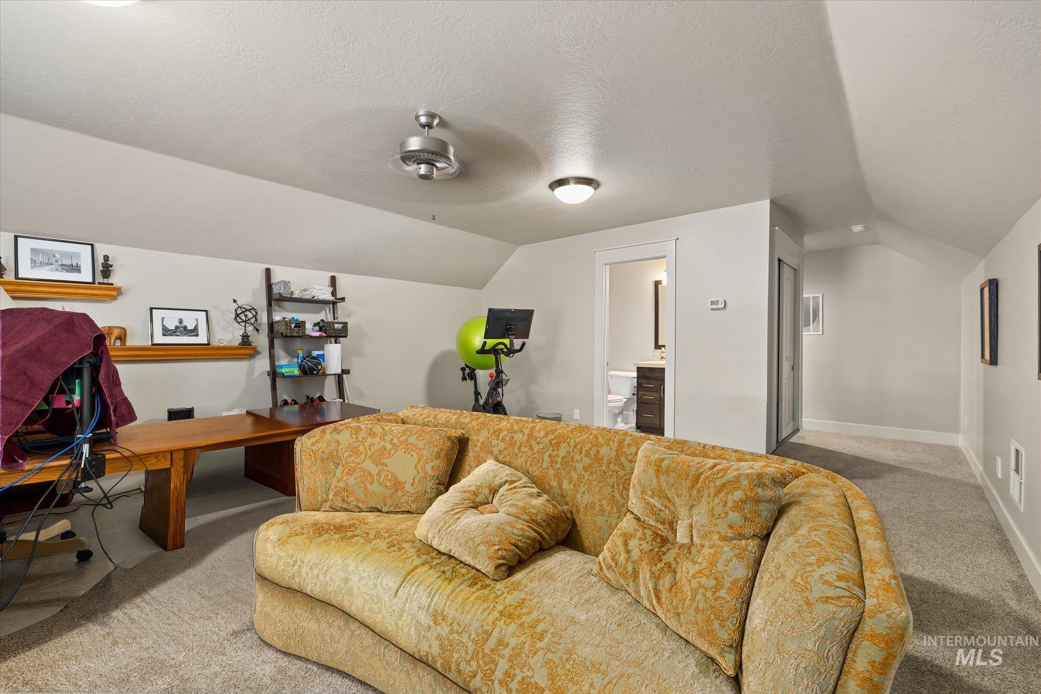Carpeted cinema with lofted ceiling, a textured ceiling, and a ceiling fan