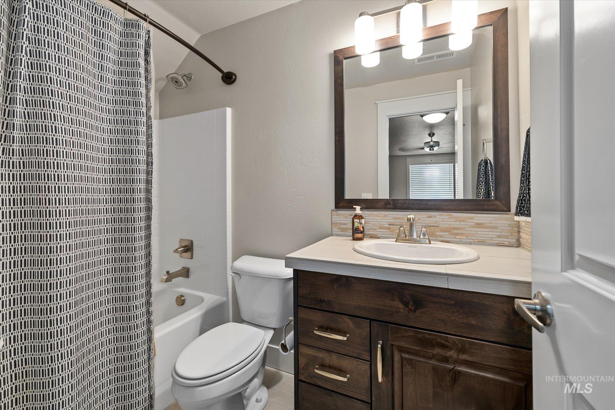 Bathroom featuring vanity, backsplash, and shower / tub combo
