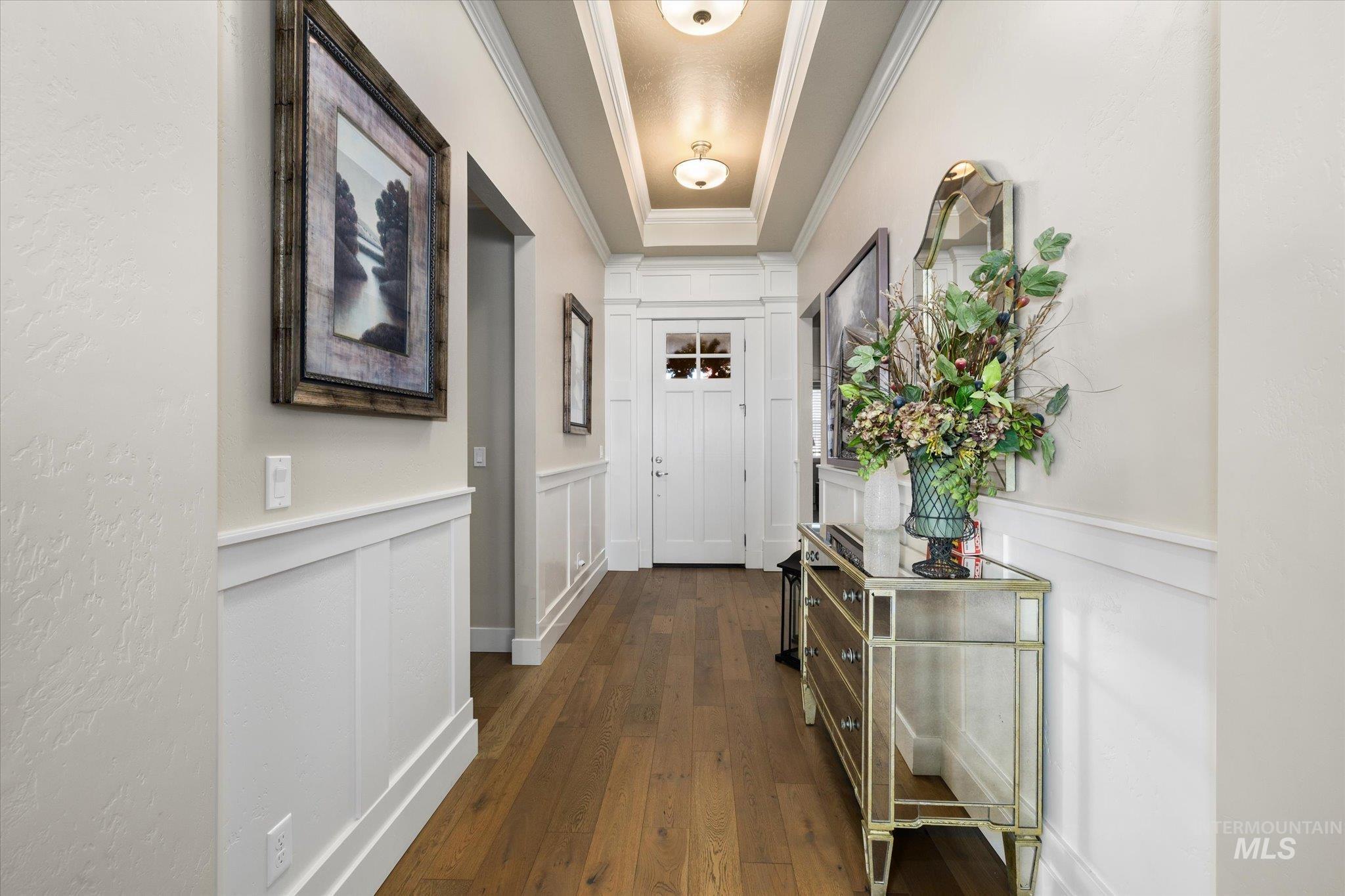 Entryway featuring a decorative wall, a wainscoted wall, ornamental molding, and hardwood / wood-style floors