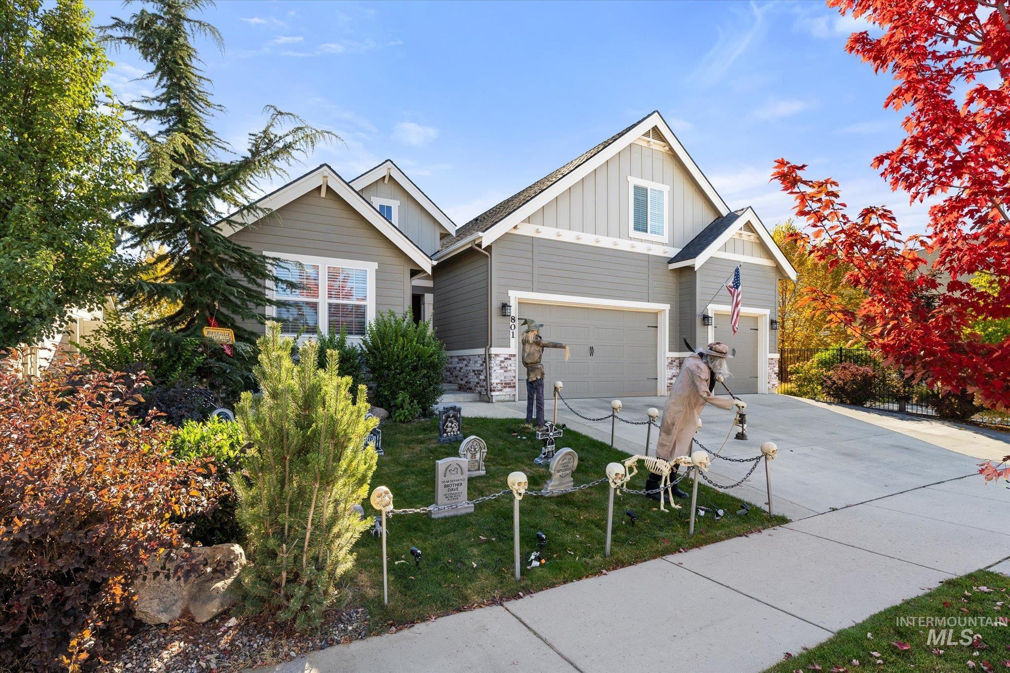 Craftsman inspired home with board and batten siding, driveway, a front lawn, and stone siding